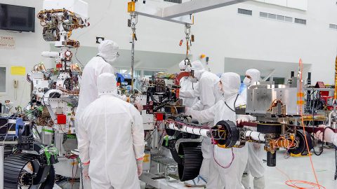 On June 21st, 2019, engineers at NASA's Jet Propulsion Laboratory install the main robotic arm on the Mars 2020 rover. Measuring 7 feet (2.1 meters) long, the arm will allow the rover to work as a human geologist would: by holding and using science tools with its turret. (NASA/JPL-Caltech)