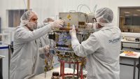 Technicians integrate NASA’s Deep Space Atomic Clock into the Orbital Test Bed Earth-orbiting satellite, which will launch on a SpaceX Falcon Heavy rocket, on June 22, 2019. (General Atomics)