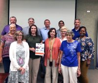 MCHC Monthly Meeting: Members and guest, Candis Batey, display the Montgomery County Mental Health Directory. (Back Row L to R) Tim Swaw, Jay Albertia, Joey Smith, Isaiah Hurtado and Rich Holladay. (Middle Row L to R) Candis Batey, Carlye Sommers, Dr. Patty Orr, Loretta Bryant and Tanya Johnson. (Front Row L to R) Patti Hill and Bertha Drew.