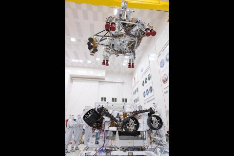 In this picture from September 2th8, 2019, engineers and technicians working on the Mars 2020 spacecraft at NASA's Jet Propulsion Laboratory in Pasadena, California, look on as a crane lifts the rocket-powered descent stage away from the rover after a test. (NASA/JPL-Caltech)