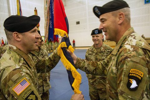 Maj. Gen. Brian Winski, Commanding General of the 101st Airborne Division (Air Assault), right, passes the brigade colors to Col. Robert G. Born, left, during 1st Brigade Combat Team’s Change of Command ceremony Nov. 22, in Sabo Physical Fitness Center on Fort Campbell, Ky. The ceremony is a time-honored military tradition that represents a formal transfer of authority and responsibility of a unit from one commanding officer to another. (Maj. Vonnie Wright, 1st Brigade Combat Team Public Affairs.) 