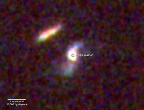 The fading afterglow of GRB 190114C and its home galaxy were imaged by the Hubble Space Telescope on Feb. 11 and March 12, 2019. The difference between these images reveals a faint, short-lived glow (center of the green circle) located about 800 light-years from the galaxy’s core. Blue colors beyond the core signal the presence of hot, young stars, indicating that this is a spiral galaxy somewhat similar to our own. (NASA, ESA, and V. Acciari et al. 2019)