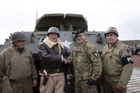 Sgt. Coleton Jones of the 2nd Brigade Combat Team, 101 Airborne Division, center, meets reenactors at a community event at the Bastogne Barracks in Bastogne, Belgium. The event took place before the parade commemorating the 75th Anniversary of the World War II Battle of the Bulge. (U.S. Army photo by Sgt, Erica Earl)