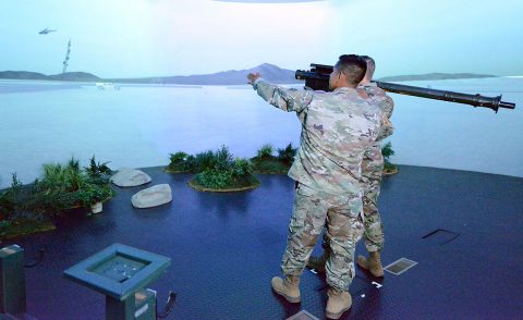 In the Stinger Dome, Staff Sgt. Ivan Peralta guides Sgt. 1st Class Arianna Cook as she aims a shoulder-fired Stinger missile at an enemy helicopter projected on the circular wall of the simulation center. A five-week class in the Man-Portable Air Defense System, or MANPADS, is being taught to infantry and armor Soldiers in a stop-gap effort to protect maneuver units from enemy aircraft, drones and cruise missiles. (Gary Sheftick) 