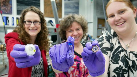 From left to right, NASA scientists Sarah Valencia, Barbara Cohen and Natalie Curran hold Moon soil samples collected by Apollo astronauts. In their lab, the Mid-Atlantic Noble Gas Research Laboratory (MNGRL) at NASA's Goddard Space Flight Center, these scientists analyze Moon soil to learn more about the evolution of the solar system. (NASA's Goddard Space Flight Center/Molly Wasser)