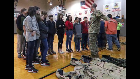 Pfc. Keneth Fouts, 74th Composite Truck Company, 129th Division Sustainment Support Battalion, 101st Airborne Division (Air Assault) Sustainment Brigade, shows students of Trigg County Middle School the different type of gear that 101st Airborne Division Soldiers wear such as wet weather gear, cold weather gear and operational camouflage pattern uniforms, Jan 28, in Cadiz, Ky. (Sgt. Aimee Nordin, 101st Airborne Division (AA) Sustainment Brigade Public Affairs)