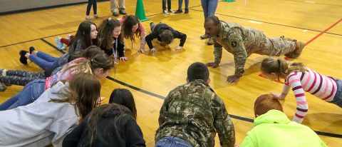 Spc. Walter Lacayo, 613th Movement Control Team, 129th Division Sustainment Support Battalion, 101st Airborne Division (Air Assault) Sustainment Brigade, leads the students of Trigg County Middle School through a warm-up exercise before their 10-meter water can challenge on Jan 28, in Cadiz, Ky. (Sgt. Aimee Nordin, 101st Airborne Division (AA) Sustainment Brigade Public Affairs)