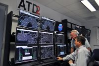 At NASA’s air traffic management laboratory near the Dallas/Ft. Worth International Airport in Texas, researchers Al Capps (seated) and Paul Borchers demonstrate Airspace Technology Demonstration 2 tools that air traffic managers have been successfully testing since 2017 at the Charlotte Douglas International Airport in North Carolina to more efficiently direct departing traffic. (NASA / Jim Banke)