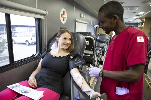 American Red Cross phlebotomist Marquis Lewis visits with Kimberly McCaw while she donates blood. (Jason Miczek, American Red Cross)