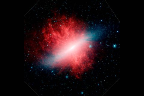 This infrared image from NASA's Spitzer Space Telescope shows Messier 82, or the "Cigar galaxy," smothered in smoky dust particles (red) blown out into space by the galaxy's hot stars (blue). (NASA/JPL-Caltech)