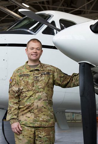 U.S. Army Reserve Chief Warrant Officer 3 Daniel Schoonmaker, a flight operations officer assigned to Company C, 2nd Battalion, 228th Aviation Regiment, 244th Expeditionary Combat Aviation Brigade, stands next to a C12-Huron plane used for executive transportation. (Sgt. Alexandra Shea)