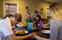 U.S. Army Reserve Chief Warrant Officer 3 Daniel Schoonmaker, assigned to 2nd Battalion, 228th Aviation Regiment, 244th Expeditionary Combat Aviation Brigade, prays with his family before enjoying dinner on March 11, 2020, at Carthage, North Carolina. The children are raised with Christian values and routinely eat meals, attend church and pray together. (Sgt. Alexandra Shea)