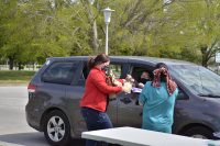 Adriene Laban, library technician, and Lisa Taylor, marketing coordinator for Fort Campbell Morale, Welfare and Recreation, hand out bags filled with crafts to Families, April 17 during the Grab-and-Go Brown Paper Bag Craft Giveaway at the Robert F Sink Memorial Library. (Emily LaForme, Fort Campbell Courier)