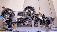 Three of the six flight wheels that will travel to Mars can be seen attached to NASA’s Perseverance rover (which is inverted on a handling fixture) on March 30, 2020 at the Kennedy Space Center in Florida. The protective antistatic foil covering the wheels will be removed before launch this summer. (NASA/JPL-Caltech)