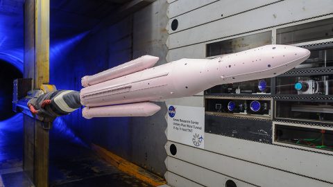 A model of the Space Launch System rocket covered in a thin coat of pink, pressure-sensitive paint is mounted in a wind tunnel at NASA's Ames Research Center. The high-tech paint acts as a pressure sensor covering the entire surface of the rocket during tests simulating its launch to space. (NASA/Ames Research Center/Dominic Hart)