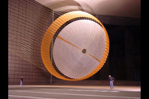 An early parachute design for the Mars Science Laboratory landing system was tested in October 2007 inside the world's largest wind tunnel at the National Full-Scale Aerodynamics Complex. In this image, two engineers are dwarfed by the parachute, which measures more than 165 feet in length and opens to a diameter of nearly 55 feet – with only about 12.5 feet of clearance to both the floor and ceiling. (NASA/JPL/Pioneer Aerospace)