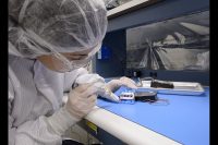 Engineers at NASA’s Ames Research Center in California’s Silicon Valley assemble the Near-Infrared Volatile Spectrometer System in preparation for its 2021 flight to the Moon. While assembling the instrument inside the NIRVSS clean room, integration engineer Amanda Cook uses ultraviolet light to inspect the four infrared detectors on the NIRVSS Longwave Calibration Sensor for cleanliness, before fastening the board into its enclosure. (NASA / Ames Research Center / Dominic Hart)