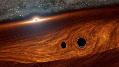 This artist's concept shows a supermassive black hole surrounded by a disk of gas. Embedded in this disk are two smaller black holes that may have merged together to form a new black hole. (Caltech/R. Hurt (IPAC))