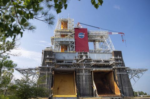 The Space Launch System (SLS) rocket is completing the Green Run test for the rocket’s core stage, shown installed on the top left side of the B-2 Test Stand at NASA’s Stennis Space Center near Bay St. Louis, Mississippi. For Green Run, the team is completing a series of eight tests culminating with Test 8, a full-up hot fire test that lasts eight minutes. Flames from the test will exit out of the yellow flame bucket shown here on the north side of the test stand. (NASA/Stennis)