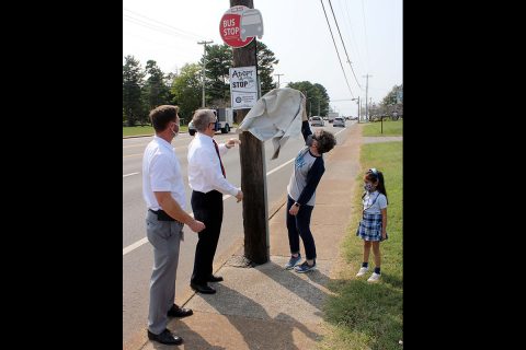 Immaculate Conception School Principal Stephanie Stafford and student Amelia Campagna help CTS Director Paul Nelson and Clarksville Mayor Joe Pitts unveil the Adopt-A-Stop sign at the CTS bus stop in front of the school.