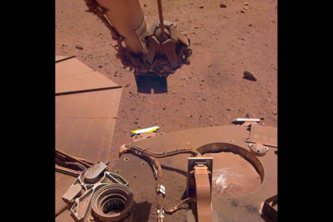 To clean a bit of dust from one of its solar panels, NASA’s InSight lander trickled sand above the panel. The wind-borne sand grains then picked up some dust on the panel, enabling the lander to gain about 30 watt-hours of energy per sol on May 22nd, 2021, the 884th Martian day of the mission. (NASA/JPL-Caltech) To clean a bit of dust from one of its solar panels, NASA’s InSight lander trickled sand above the panel. The wind-borne sand grains then picked up some dust on the panel, enabling the lander to gain about 30 watt-hours of energy per sol on May 22nd, 2021, the 884th Martian day of the mission. (NASA/JPL-Caltech)