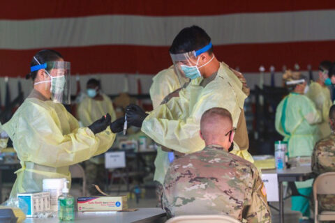 Specialist Hanul Yi, left, receives a sample for COVID-19 pool testing from Cpl. Evan Scott at Hangar 3, August 23rd, 2020. Both Soldiers are medics assigned to A Company, 1st Battalion, 327th Infantry Regiment, 1st Brigade Combat Team, 101st Airborne Division (Air Assault). (Courtesy Photo, Fort Campbell Public Affairs Office)