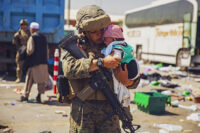 A Marine holds a baby while a family in-processes at Hamid Karzai International Airport, Kabul, Afghanistan, August 28th, 2021. U.S. service members are assisting the Department of State with a non-combatant evacuation operation in Afghanistan. (Marine Corps Staff Sgt. Victor Mancilla)