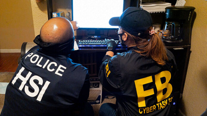 Investigators from Homeland Security Investigations and the FBI conduct a search on a computer.