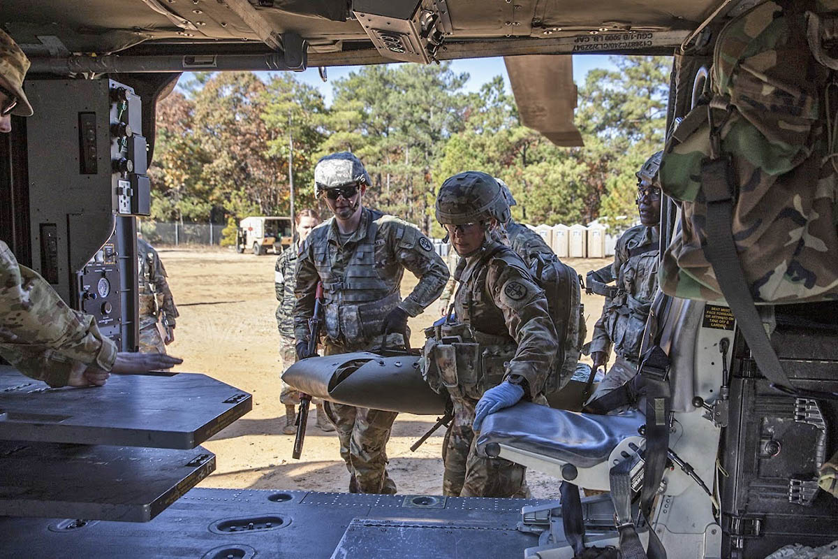 U.S. Army Capt. Gayle Benton, left, and 1st Lt. Allan Nkrumah, assigned to Dwight D. Eisenhower Army Medical Center, Fort Gordon, Georgia, load a simulated injured teammate into a medical evacuation helicopter during a Multiple Objectives Lane event as part of the Regional Health Command-Atlantic 2021 Best Medic Competition, Fort Bragg, North Carolina, Nov. 16, 2021. Eleven two-soldier teams competed at the Regional Health Command-Atlantic 2021 Best Medic Competition, and the winning team will move on to represent the region at the U.S. Army Medical Command’s 2022 Command Sgt. Maj. Jack L. Clark, Jr. U.S. Army Best Medic Competition at Fort Hood, Texas, Jan. 24-28, 2022. (Spc. Rhianna Ballenger)