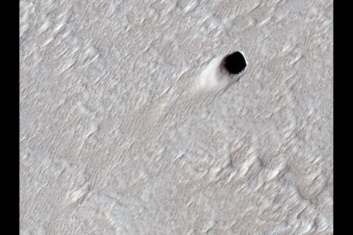This pit crater was created by an empty lava tube in Mars’ Arsia Mons region. The image was captured by NASA’s Mars Reconnaissance Orbiter on Aug. 16, 2020. (NASA/JPL-Caltech/University of Arizona) This pit crater was created by an empty lava tube in Mars’ Arsia Mons region. The image was captured by NASA’s Mars Reconnaissance Orbiter on Aug. 16, 2020. (NASA/JPL-Caltech/University of Arizona)