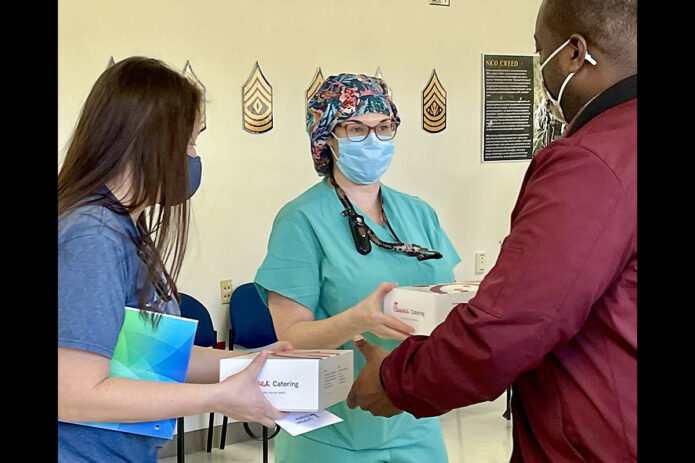 LifePoint Church Pastor Willie Simpson passes a boxed lunch to a Blanchfield Army Community Hospital staff member in the hospital’s Command Sergeant Major Classroom, February 14th. Church officials brought the lunches to feed healthcare workers at the hospital in appreciation for their COVID-19 response efforts in the community. (Maria Christina Yager, Blanchfield Army Community Hospital)
