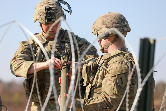 Army Spc. Edwin Miranda and Army Sgt. Kyle Moitoza, both of Bravo Company, 1st Brigade Engineer Battalion, 1st Armored Brigade Combat Team, 1st Infantry Division, prepare an explosive as part of range detonation training, at Swietoszow Range, Poland, March 21st, 2022. (Army Sgt. Joseph Aleman)