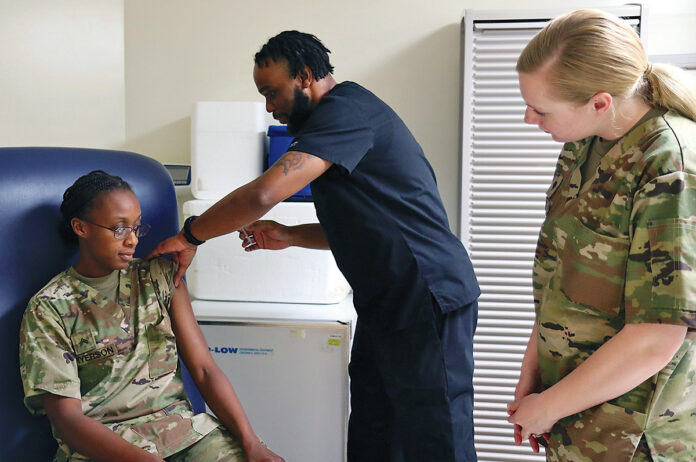 Jonathan Simmons, licensed practical nurse, LaPointe Army Medical Home at Fort Campbell, Ky., shows Spc. Megan Behre, 526th Brigade Support Battalion, 2nd Brigade Combat Team, 101st Airborne Division (Air Assault), right, how to administer a shot May 10 during immunization training. Cpl. Desiree Fryerson, 1st Battalion, 26th Infantry Regiment, 2nd BCT, acted as the patient during the demonstration. (Ethan Steinquest)