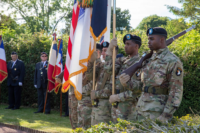 U.S. Army Soldiers with the 101st Airborne Division hold the U.S. Flag during a ceremony to honor paratroopers who died in an airplane crash during D Day operations in Beuzeville au Plain, France, June 1, 2022. During D Day operations a C47 carrying 17 paratroopers was hit by anti-aircraft fire and crash landed, killing 5 crew and the paratroopers. (Staff Sgt. Alexander Skripnichuk, U.S. Army)