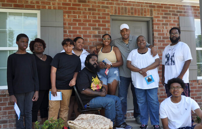 New homeowner Dontrel Washington (seated, center) is surrounded by friends and family during his dedication ceremony on Saturday, June 11th.