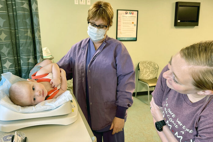 Mom & Me participant, Pfc. Jacqueline Kerchner smiles at her son, while Registered Nurse, Ms. Lesli Eiland, a certified lactation consultant, gets his post-feeding weight during Blanchfield Army Community Hospital’s breastfeeding support group, July 11. Lactation support personnel at military treatment facilities or through TRICARE are available to help service members and other TRICARE Prime and TRICARE Select beneficiaries reach their breastfeeding or lactation goals.