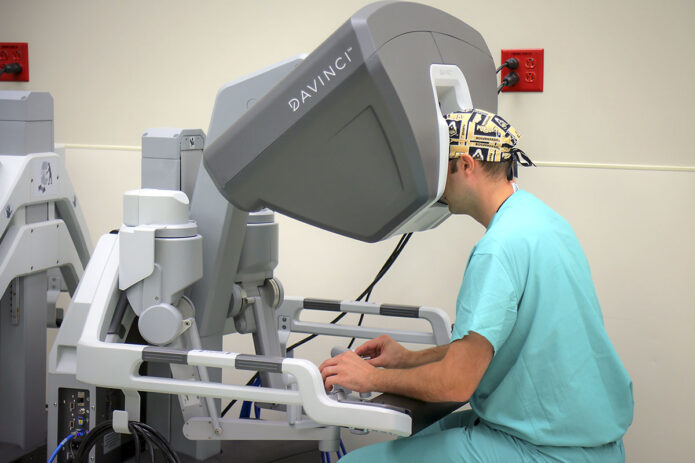 Army Surgeon Maj. (Dr.) Morgan Barron, a general surgeon at Blanchfield Army Community Hospital sits at the surgeon console of a robotic surgical system, July 6. Barron began performing robotically-assisted surgery more than 10 years ago during his general surgery residency training at Madigan Army Medical Center, Joint Base Lewis-McChord, Washington and he is working to bring the capability to Fort Campbell. (U.S. Army photo by Justin Moeller)