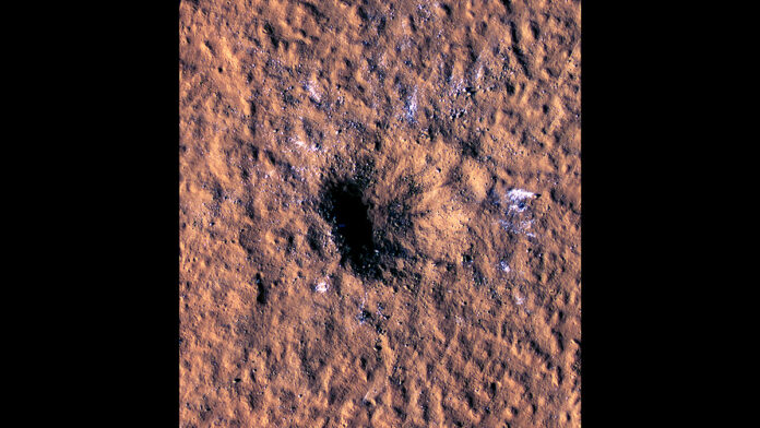 Boulder-size blocks of water ice can be seen around the rim of an impact crater on Mars, as viewed by the High-Resolution Imaging Science Experiment (HiRISE camera) aboard NASA’s Mars Reconnaissance Orbiter. The crater was formed Dec. 24, 2021, by a meteoroid strike in the Amazonis Planitia region. (NASA/JPL-Caltech/University of Arizona)