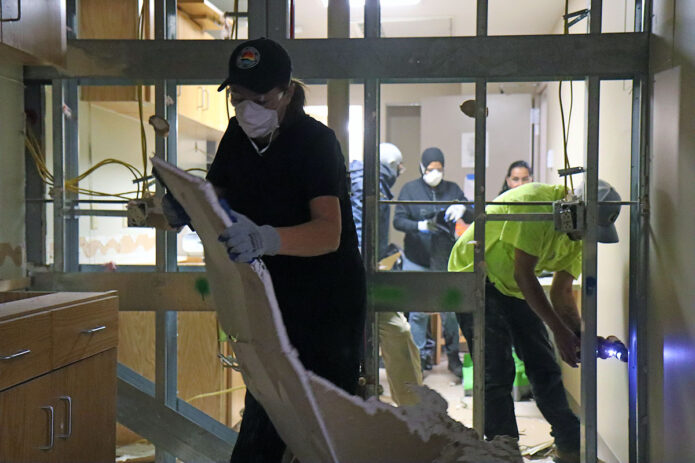 Local contract workers clean up the area after demolishing a section of water-damaged drywall Jan. 3 in barracks Building 7932. The facility sustained significant water damage from a burst fire suppression pipe after a wave of freezing temperatures Dec. 23-27, and the Directorate of Public Works aims to have the building repaired by the time the Soldiers who live there return from the field in February. (Ethan Steinquest, Fort Campbell Public Affairs Office)