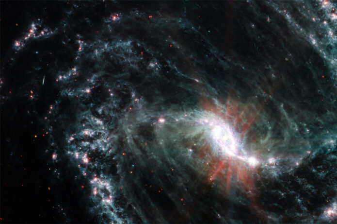 In this MIRI image of galaxy NGC 1365, clumps of dust and gas in the interstellar medium have absorbed the light from forming stars and emitted it back out as infrared light. This illuminates an intricate network of cavernous bubbles and filamentary shells. (NASA, ESA, CSA, and J. Lee (NOIRLab). Image processing: A. Pagan (STScI))