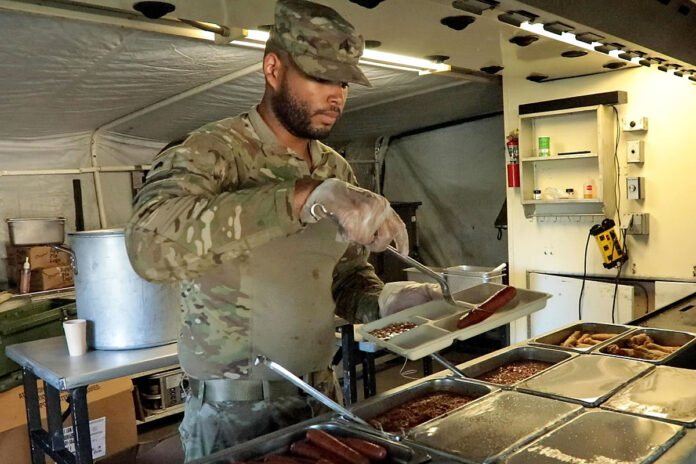 Sgt. Noah Morris, culinary specialist from the 619th Quartermaster Company, 129th Division Sustainment Support Battalion, 101st Division Sustainment Brigade “Lifeliners,” 101st Airborne Division (Air Assault), serves a special meal of hot dogs and hamburgers for the Soldiers of the 101st during Operation Lethal Eagle III, August 10th, 2023, Fort Campbell, KY. (Spc. Zachery Blevins, 101st Airborne Division (Air Assault))
