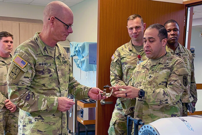 BACH Occupational Therapy Specialist Staff Sgt. Luis Diaz shows Commanding General, U.S. Army Medical Readiness Command, East, and Director, Defense Health Network East Brig. Gen. Lance Raney an early prototype of a simulated M-4 rifle charging handle, Nov. 6. The hospital’s OT staff fabricated several prototypes which attach to a strength-training machine to simulate real-life tasks for Soldiers recovering from traumatic hand and upper extremity injuries.