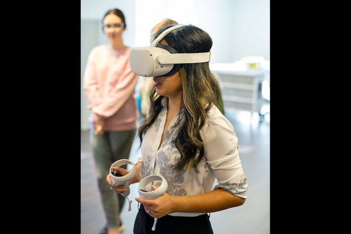 Dr. Hanrui He, education assistant professor and coordinator of the Furniture Connection EdTech Studio, sets up a virtual reality headset for a recent class demonstration at Austin Peay State University. (Sean McCully, APSU)