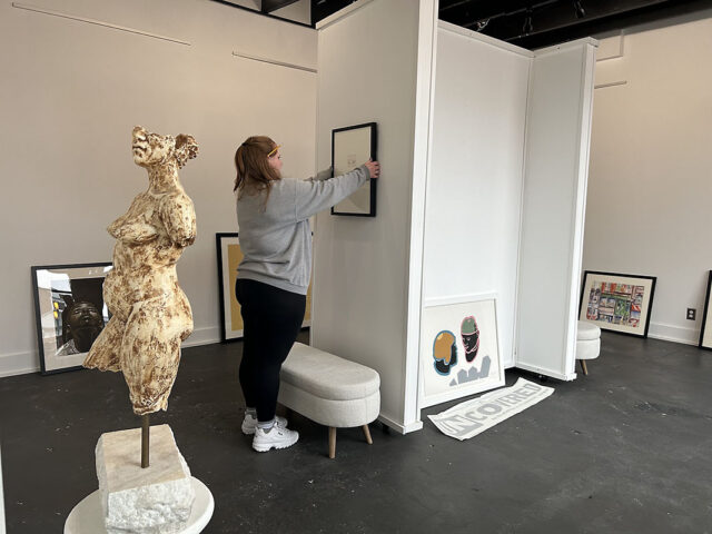 Art history major Mai Mai Newberry works to install UNCOVERED, an exhibit highlighting pieces from the Austin Peay Art Collection, in the Lorenzo Swinton Gallery. (APSU)