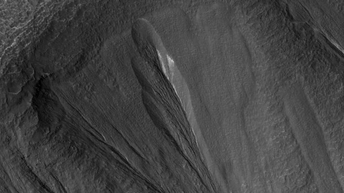 The white edges along these gullies in Mars’ Terra Sirenum are believed to be dusty water ice. Scientists think meltwater could form beneath the surface of this kind of ice, providing a place for possible photosynthesis. This is an enhanced-color image; the blue color would not actually be perceptible to the human eye. (NASA/JPL-Caltech/University of Arizona)