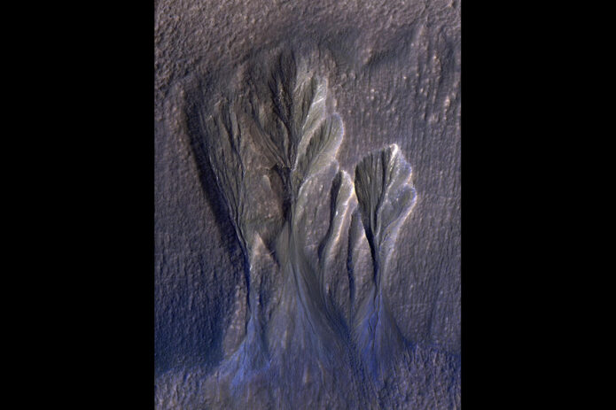 The white edges along these gullies in Mars’ Terra Sirenum are believed to be dusty water ice. Scientists think meltwater could form beneath the surface of this kind of ice, providing a place for possible photosynthesis. This is an enhanced-color image; the blue color would not actually be perceptible to the human eye. (NASA/JPL-Caltech/University of Arizona) The white edges along these gullies in Mars’ Terra Sirenum are believed to be dusty water ice. Scientists think meltwater could form beneath the surface of this kind of ice, providing a place for possible photosynthesis. This is an enhanced-color image; the blue color would not actually be perceptible to the human eye. (NASA/JPL-Caltech/University of Arizona)
