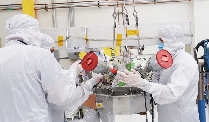 Engineers on NASA’s Europa Clipper mission work with the spacecraft’s star trackers in a clean room at the agency’s Jet Propulsion Laboratory in 2022. Used for orienting the spacecraft, the star trackers are seen here with red covers to protect their lenses. (NASA/JPL-Caltech)