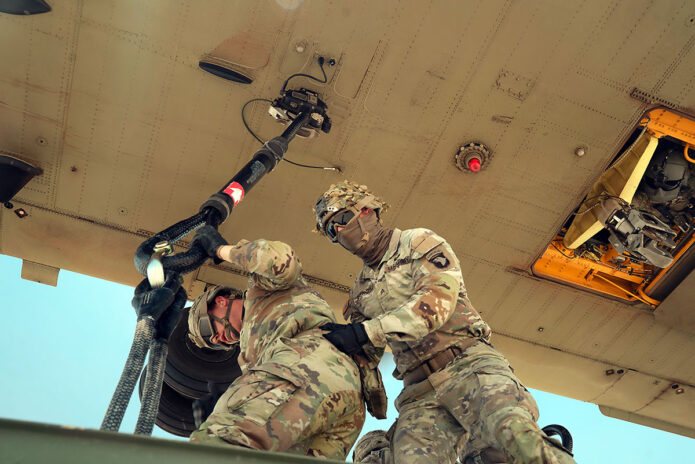 From left, U.S. Soldiers Sgt. Allen Miller and Sgt. Connor French, assigned to Charlie Company, 264th Combat Sustainment Support Battalion, 101st Division Sustainment Brigade, hooks up a container carrying supplies to a CH-47 Chinook as part of a sling load training exercise. (U.S. Army photo by 1st Lt. Marcelo Marta)