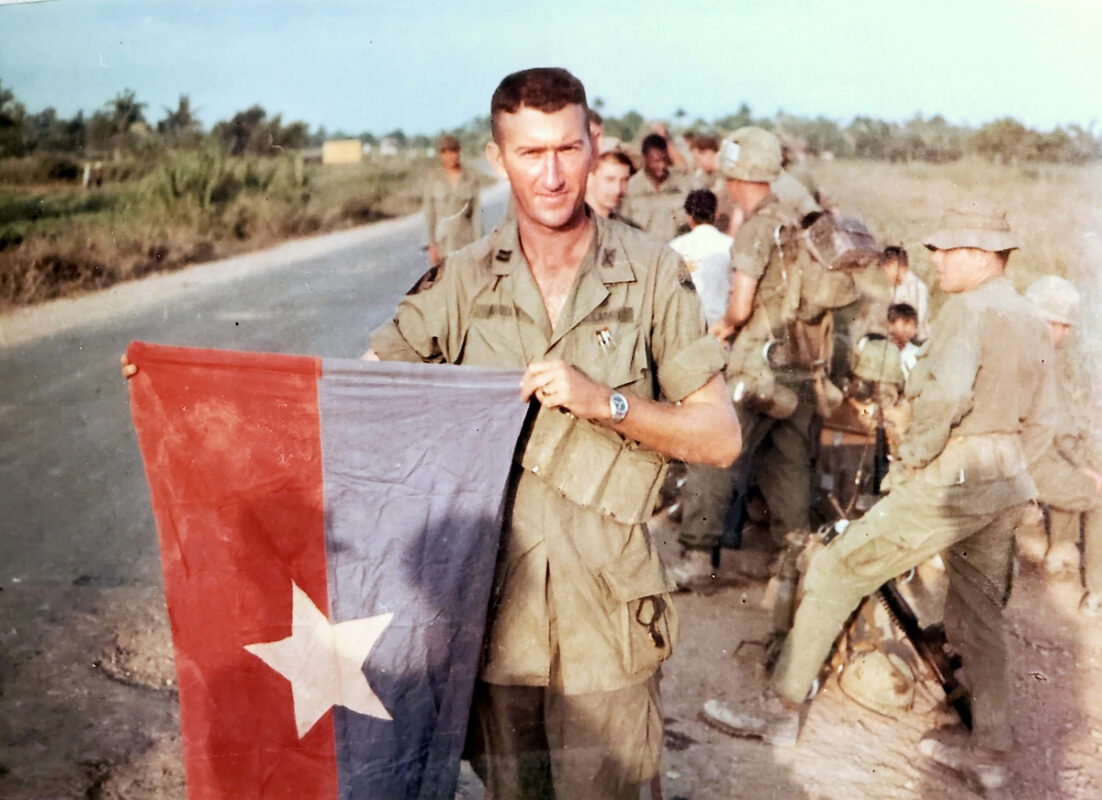 Captain Mauldin holding a Viet Cong flag after capturing a village