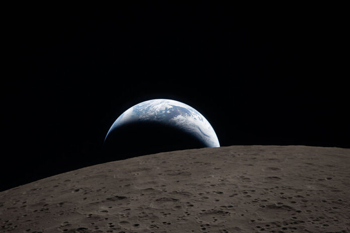 Earthset captured through the Orion spacecraft window at 6:41pm ET, April 6th, 2026, during the Artemis II crew’s flyby of the Moon. A muted blue Earth with bright white clouds sets behind the cratered lunar surface. The dark portion of Earth is experiencing nighttime. On Earth’s day side, swirling clouds are visible over the Australia and Oceania region. In the foreground, Ohm crater has terraced edges and a flat floor interrupted by central peaks. Central peaks form in complex craters when the lunar surface, liquefied on impact, splashes upwards during the crater’s formation. (NASA)